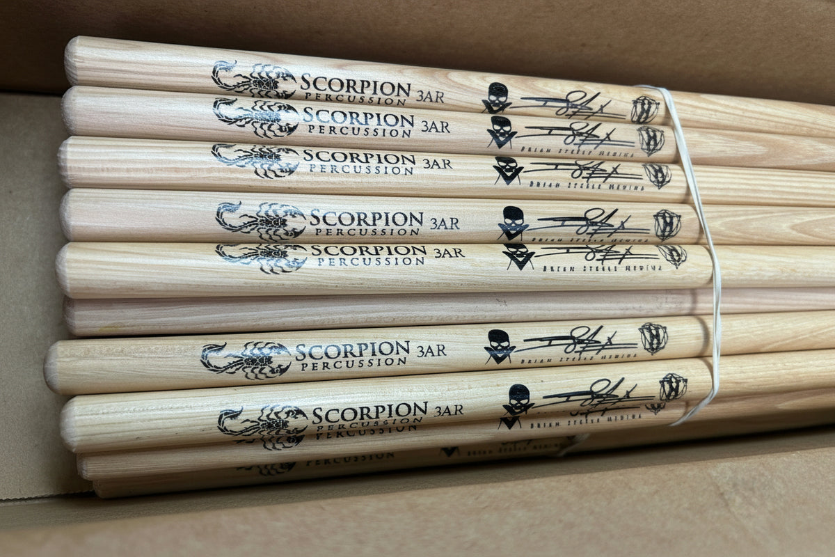 Set of Scorpion percussion wooden drumsticks with 'Scorpion' branding in a clear plastic holder.