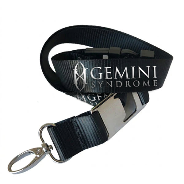 A black nylon lanyard strap with a silver metal buckle and key ring, featuring the words 'Gemini Syndrome' printed in a white.